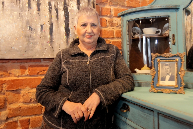L. Baranauskienė stovi šalia nuotraukos, kurioje įamžintas jos vyras jaunystėje.